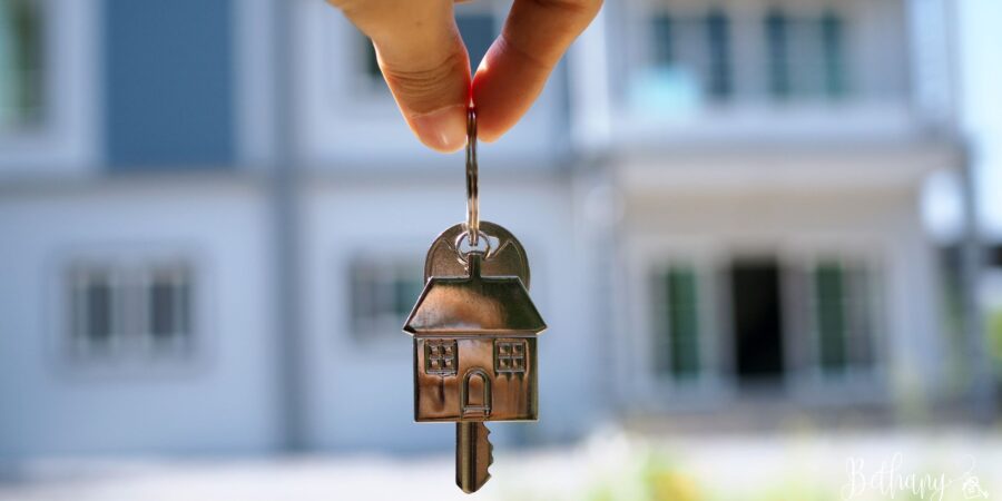 A person holding keys in front of a newly sold home
