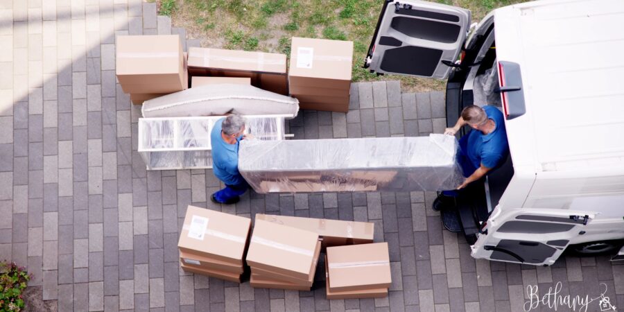 A moving truck parked partly under the bright Las Vegas sun as two movers take items out