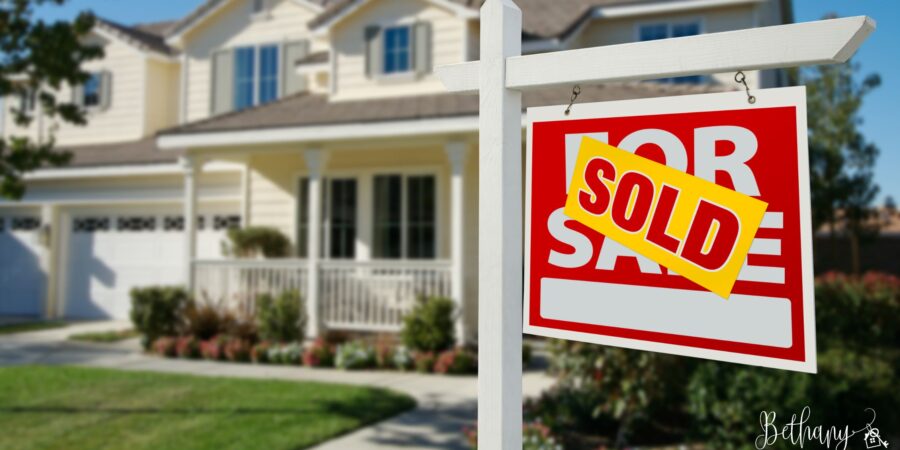 Front yard of a sunny, staged home with a ‘For Sale’ sign during summer